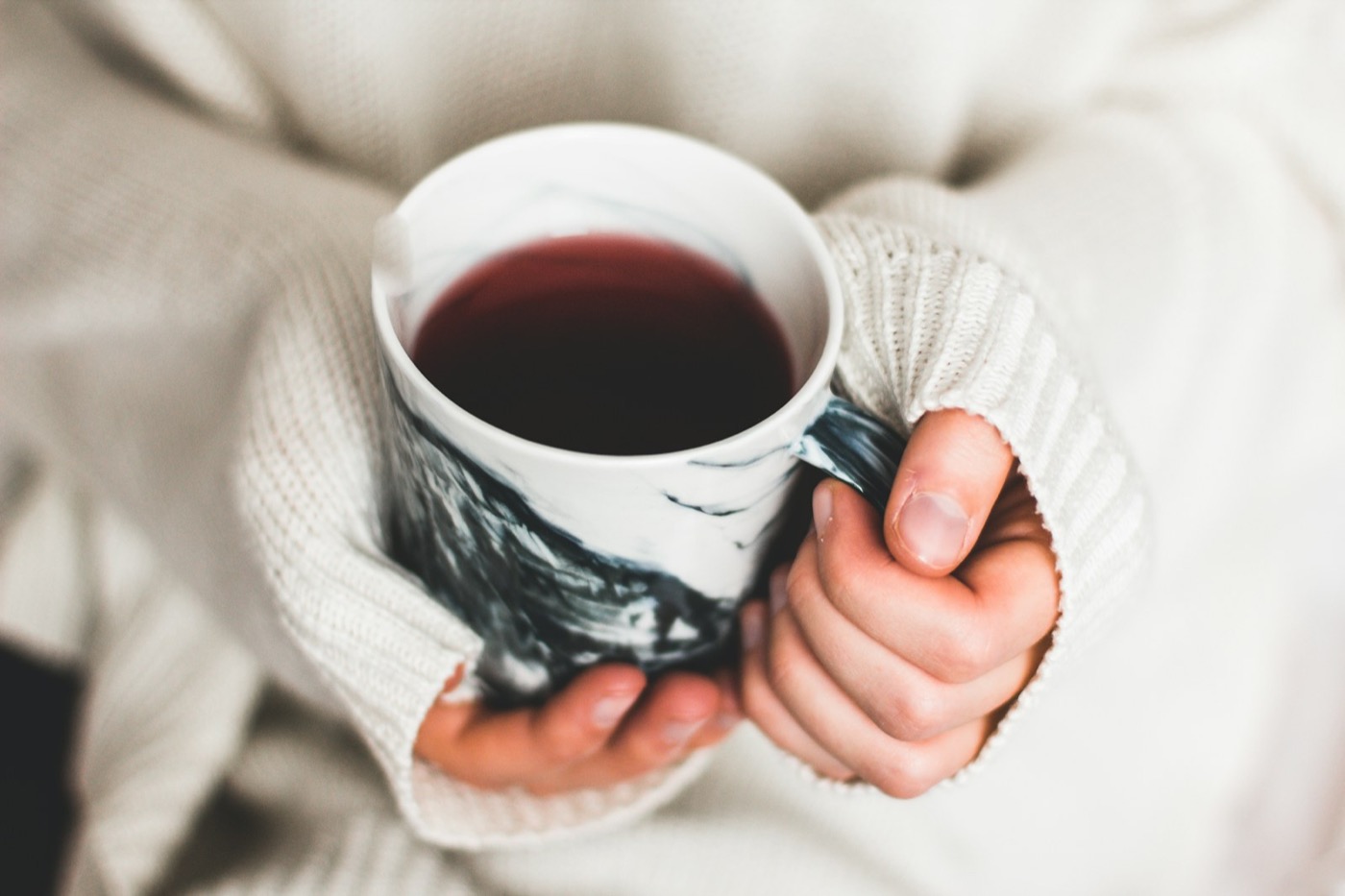 Hands cradling a warm mug in a soft knitted jumper