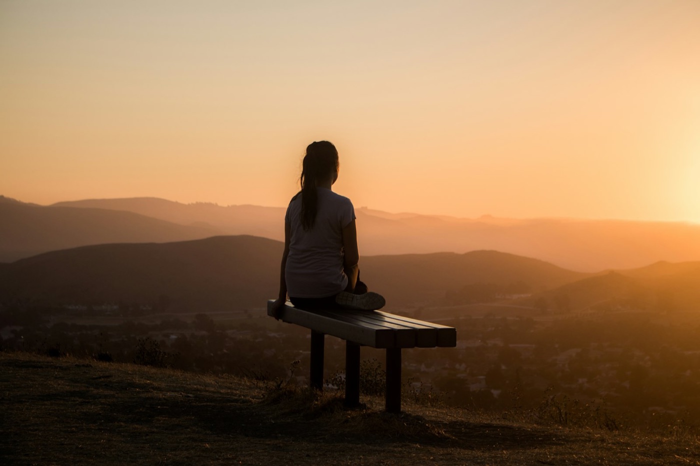 Woman sitting peacefully overlooking hills
